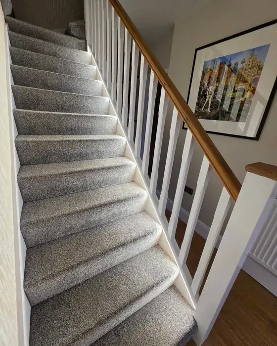 Carpeted staircase with a white banister and a warm LED strip light running along the stair string, operated by a movement sensor, in a Wirral home